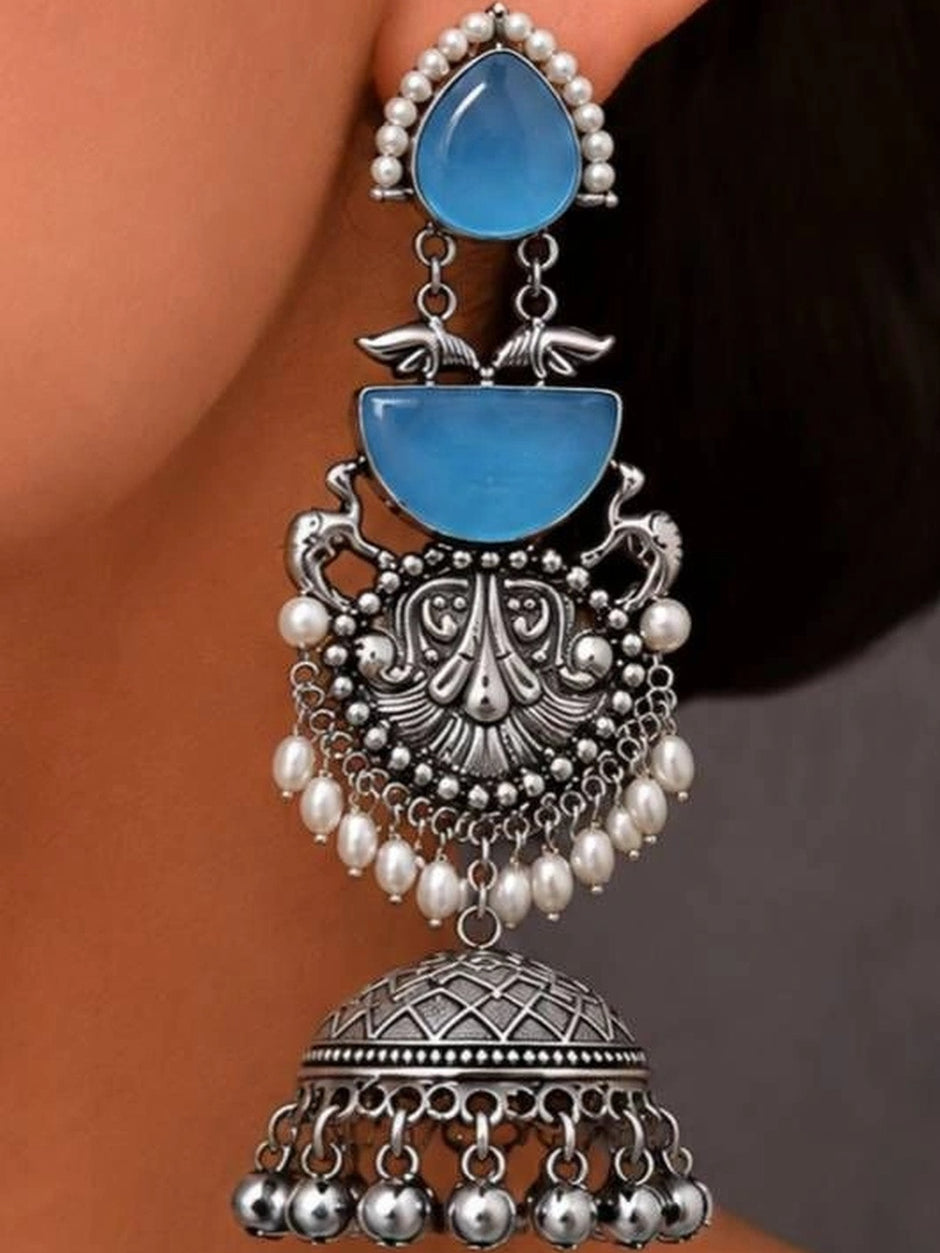 Oxidised silver jhumka earring worn on ear showing blue stone, pearl fringe and dome bell