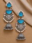 Pair of blue stone oxidised silver jhumka earrings laid flat on beige fabric