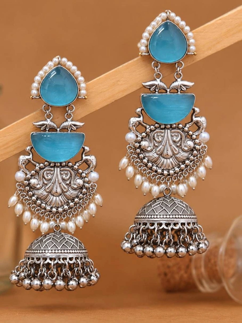 Two jhumka earrings propped against a wooden stick showing full layered drop design