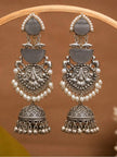 Pair of oxidised silver jhumka earrings with grey cat-eye stones and pearl drops displayed on a wooden ring stand
