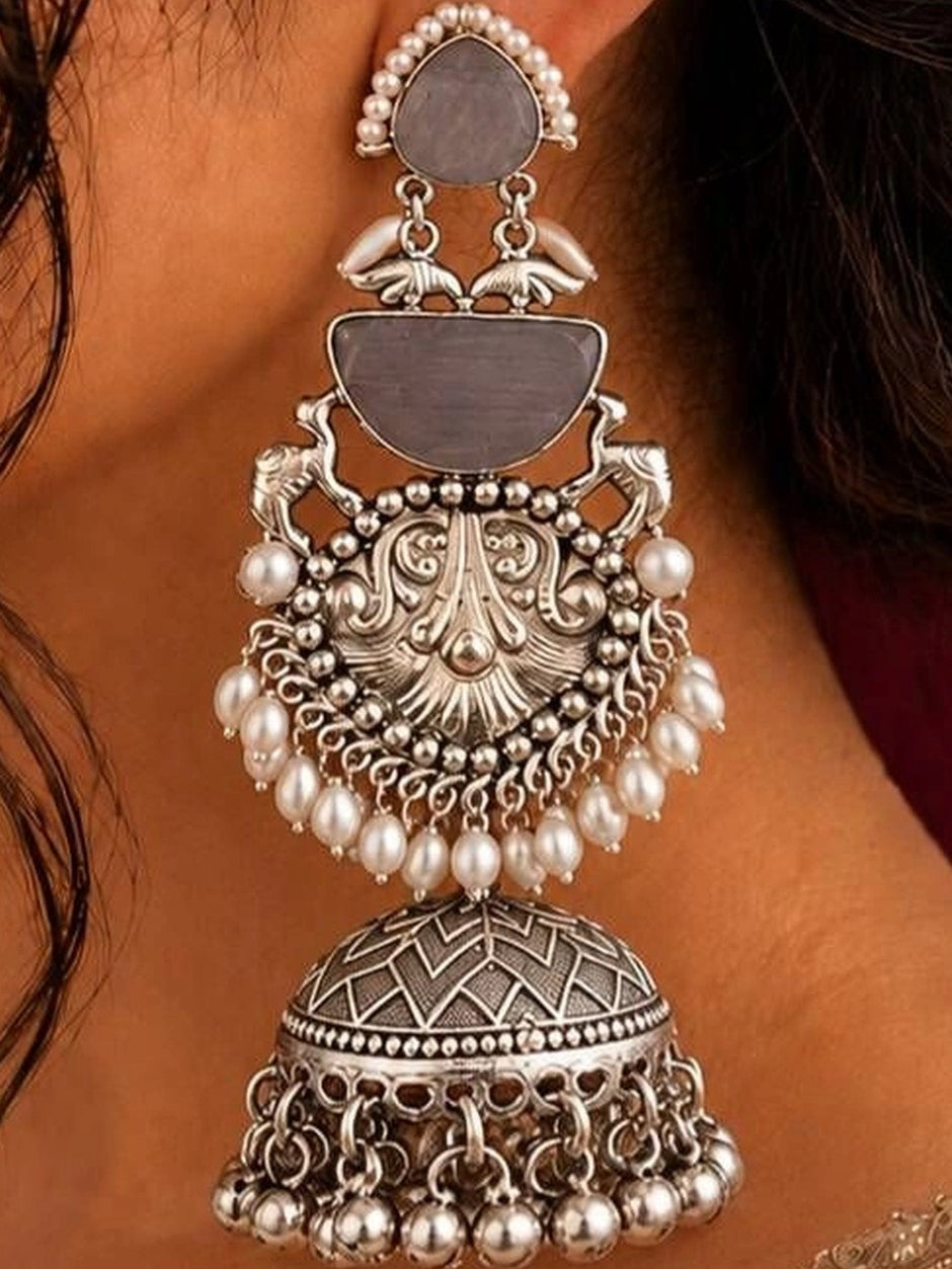 Close-up side view of one oxidised silver pearl jhumka earring worn on a woman's ear