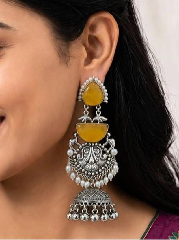 Model wearing three-tier oxidised silver chandbali jhumka with yellow stone and pearl drops on ear