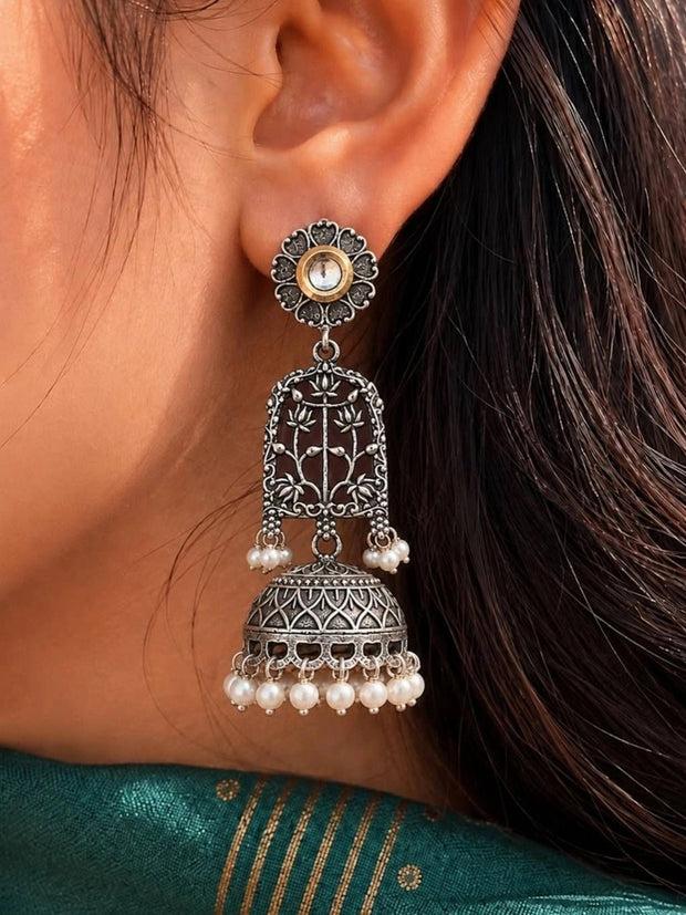 Oxidised silver lotus jhumka earring worn on ear, styled with a teal silk saree