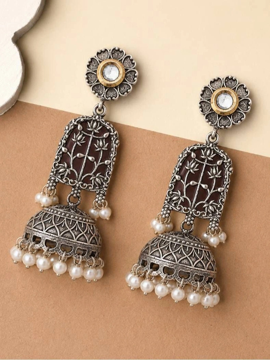 Pair of oxidised silver lotus jhumka earrings laid flat showing front and back on beige surface