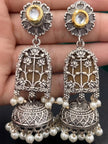 Pair of oxidised silver lotus jhumka earrings with kundan tops and pearl drops held in a hand