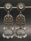 Front view of oxidised silver lotus jhumka earrings displayed on a silver rod against dark background