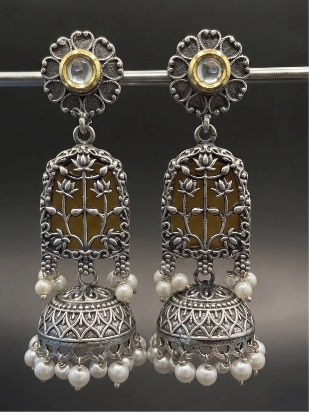Front view of oxidised silver lotus jhumka earrings displayed on a silver rod against dark background