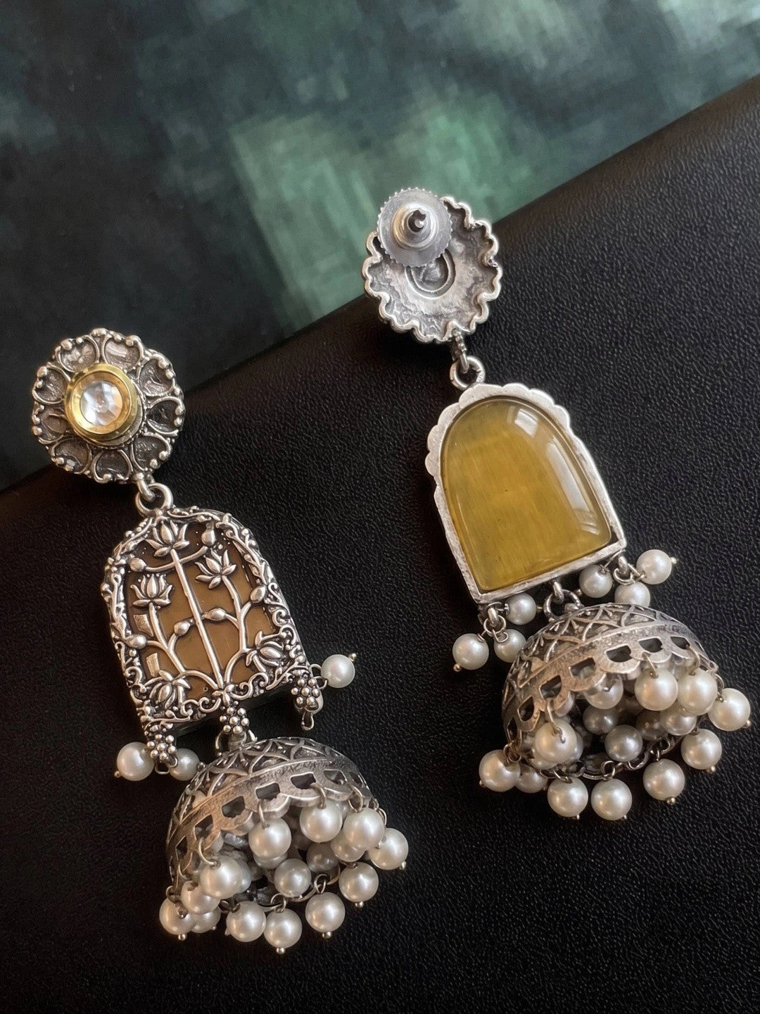 Back view of oxidised silver jhumka earrings showing screw fastening and amber resin reverse panel