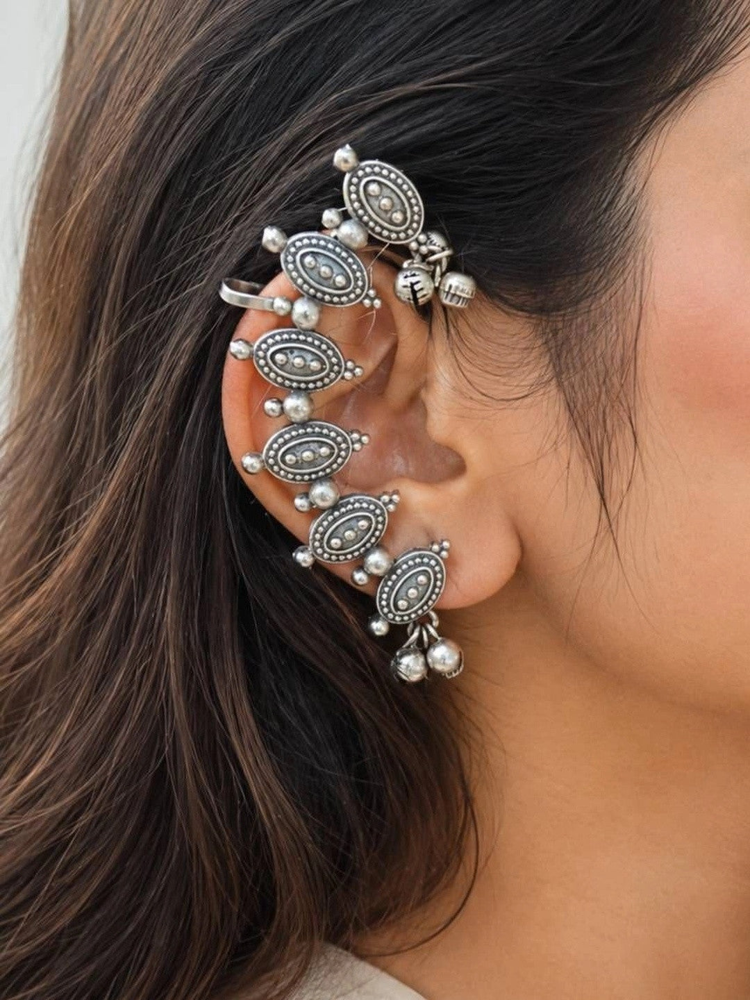 Front and back view of oxidised silver ear cuff pair laid flat, showing dotted oval motifs and adjustable cuff bands