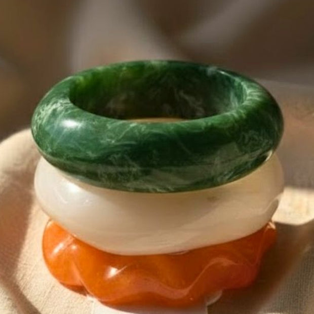 Close-up of green, white and orange marble resin bangles stacked on a linen pouch card