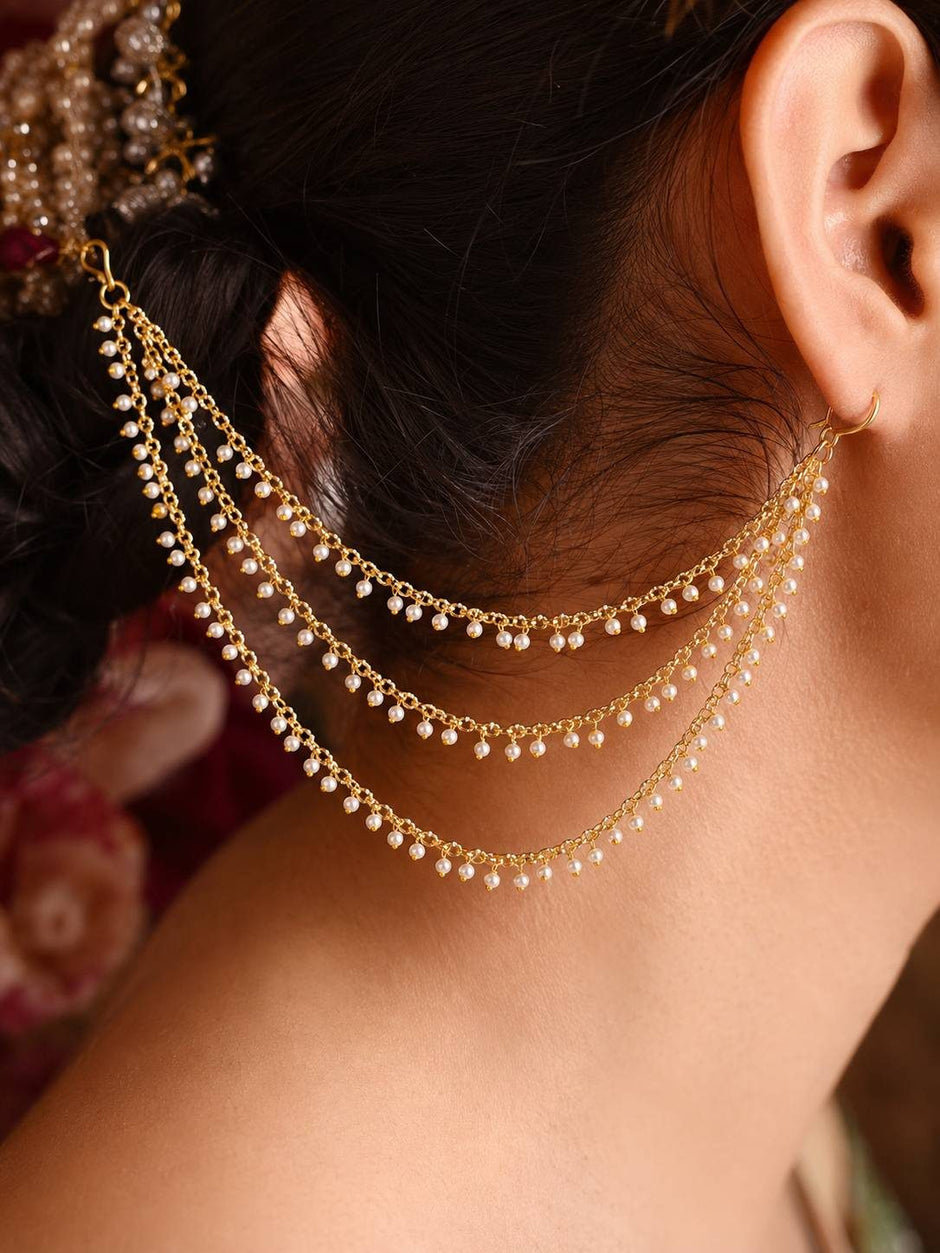 Gold-plated pearl ear chain worn on a woman showing it draped from hair to earlobe against her neck