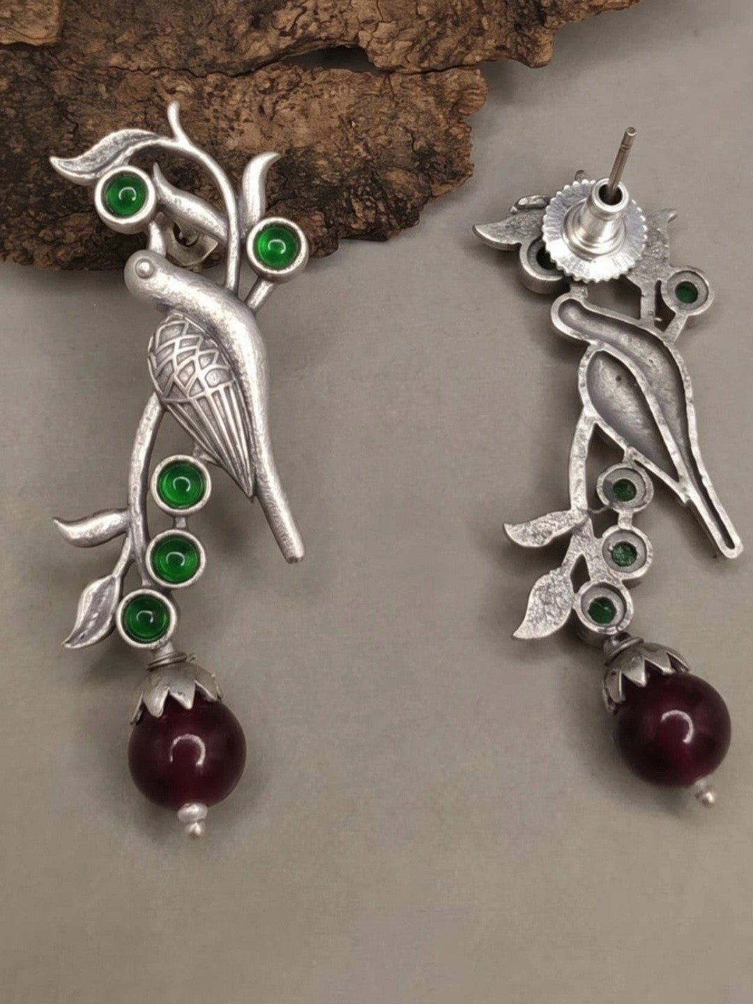 Front and back view of oxidised silver bird earrings showing stud fitting and green stone details