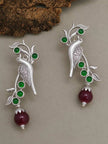 Pair of oxidised silver parrot earrings with green cabochon stones and burgundy drop bead on grey surface