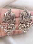 Pair of oxidised silver elephant drop earrings with oval and round faux pearl strands held in a palm