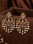 Pair of gold-plated kundan chandbali earrings with floral top and pearl fringe displayed upright in a wooden box