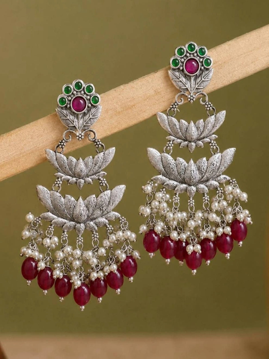 Oxidised silver lotus chandbali earrings displayed on wooden surface showing tiered lotus design
