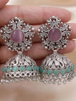 Close-up of two oxidised silver jhumka earrings held in hand showing elephant engraving turquoise beads and pearl drops