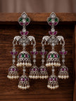 Pair of oxidised silver triple jhumka earrings displayed against dark wooden background showing stone and bell detail