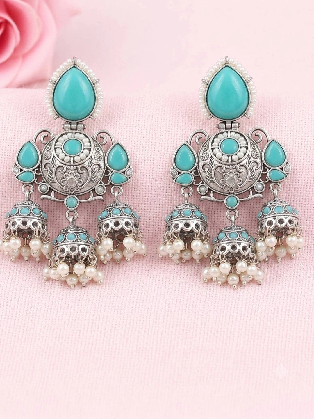 Close-up pair of triple jhumka earrings with turquoise stones and pearl bead drops