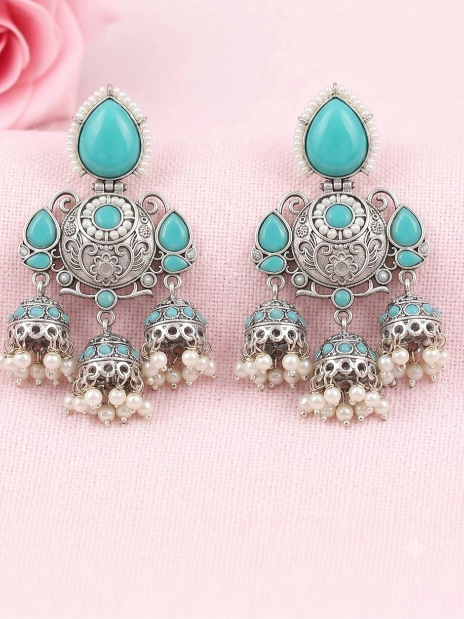 Close-up pair of triple jhumka earrings with turquoise stones and pearl bead drops