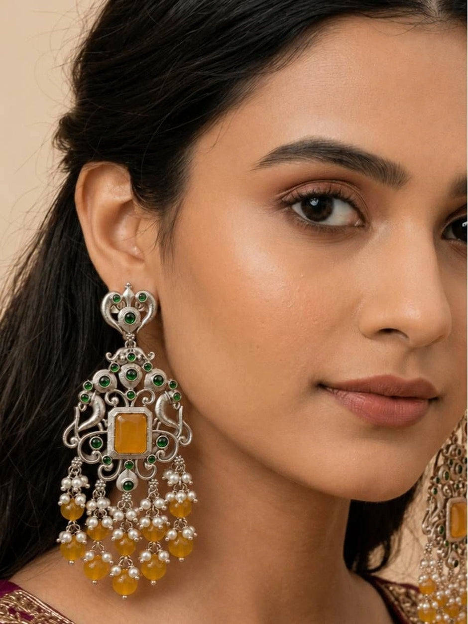 Model wearing oxidised silver chandbali earring with yellow stone centre and green accent stones