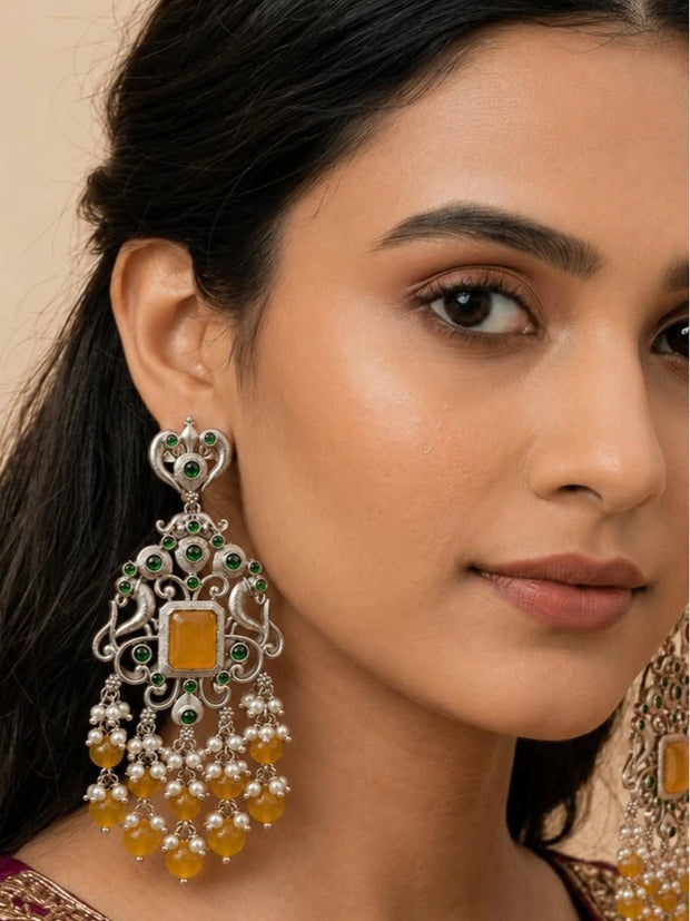 Model wearing oxidised silver chandbali earring with yellow stone centre and green accent stones