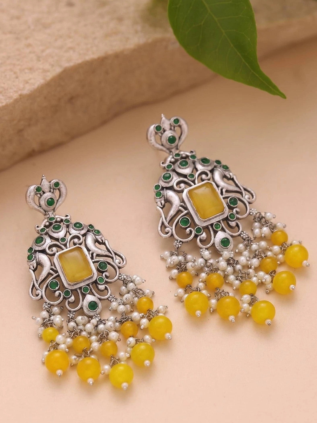 Front view of pair of oxidised silver chandbali earrings with yellow bead and pearl tassels