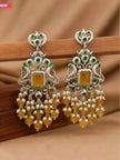 Pair of oxidised silver chandbali earrings resting on a wooden surface with yellow bead fringe