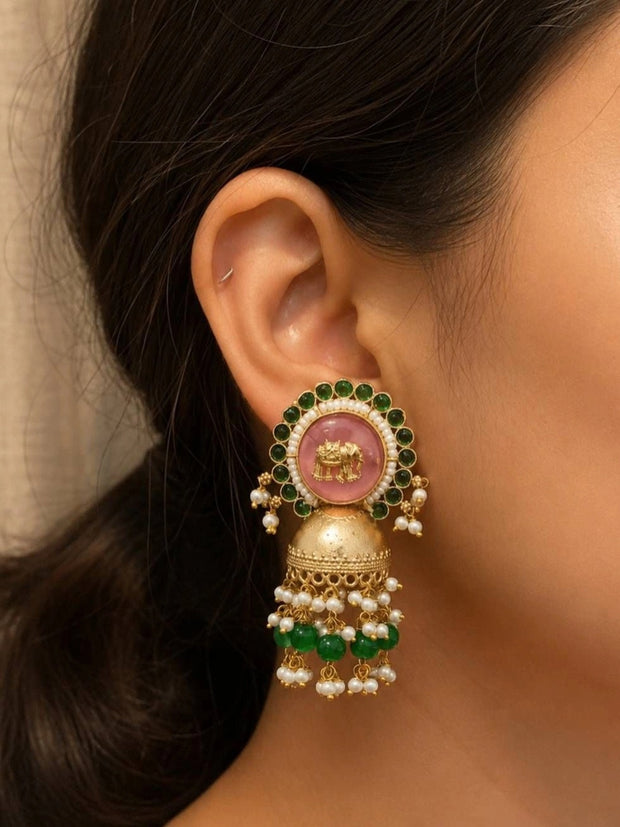 Gold-plated pink stone elephant jhumka worn on ear, showing green bead halo and pearl fringe drop
