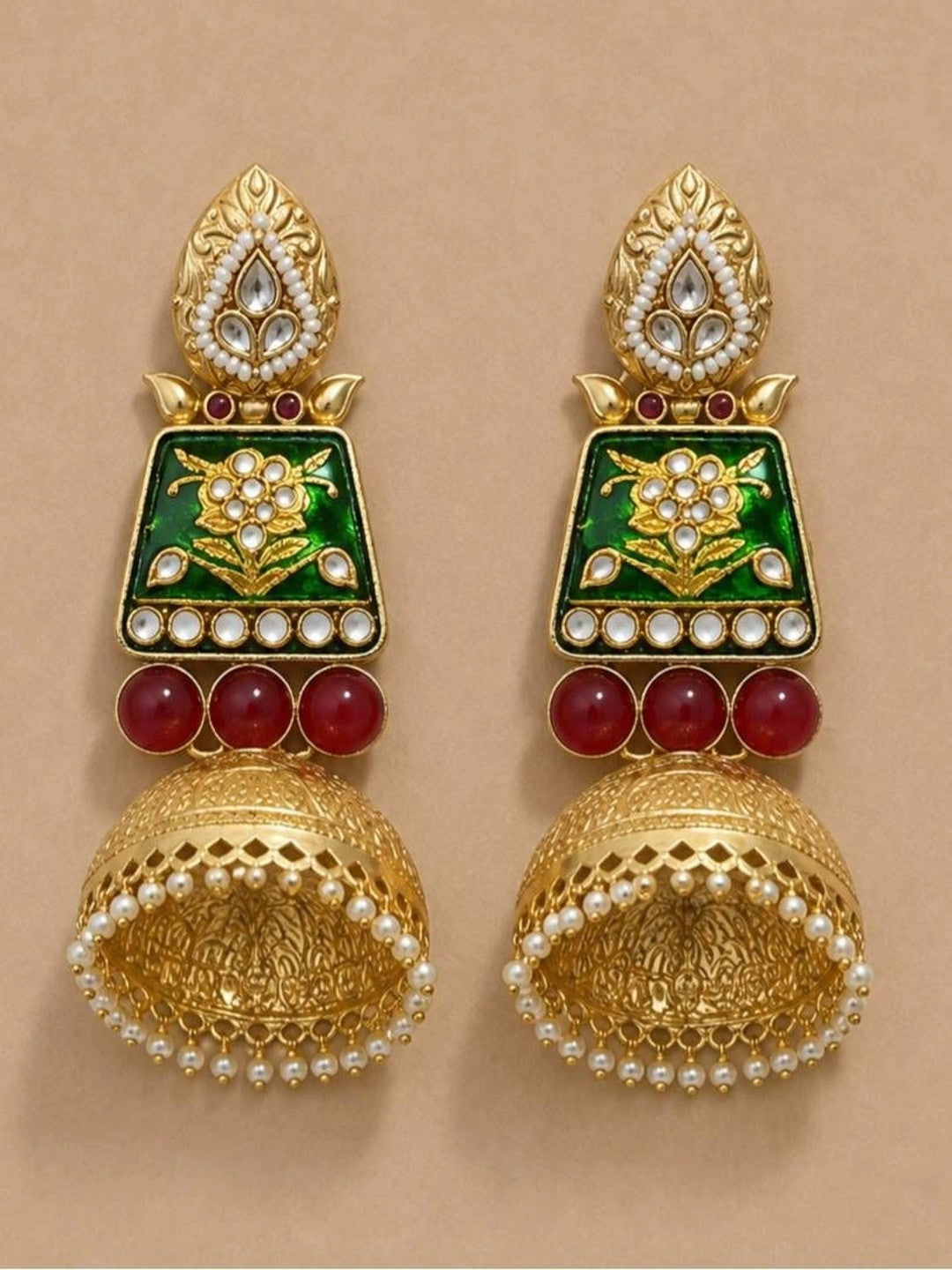 Both jhumka earrings laid flat on a beige surface, displaying leaf stud tops, green enamel panels and lattice dome bells