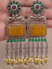 Both oxidised silver chandbali earrings held in palm showing full front detail of green stones, yellow centre and pearl drops