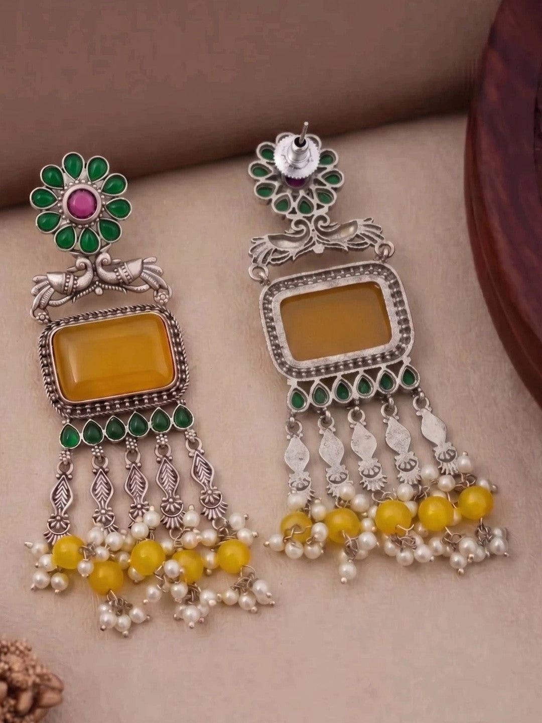 Front and reverse side of oxidised silver chandbali earrings showing push-back stud and plain back of yellow stone frame