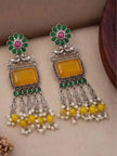 Pair of oxidised silver chandbali earrings laid flat showing engraved leaf dangles and yellow bead and pearl drop fringe