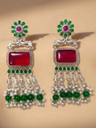 Pair of oxidised silver chandbali earrings with ruby stone, green beads and white pearl drops on beige surface