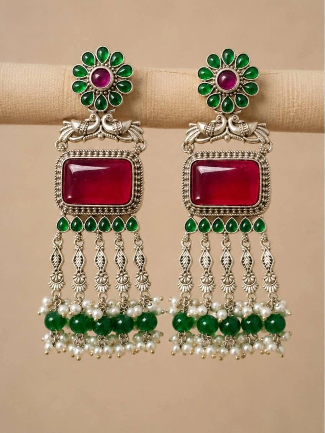 Pair of oxidised silver chandbali earrings displayed on fabric roll showing full tassel length