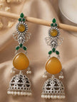 Pair of long silver jhumka earrings with amber yellow stones hanging from a wooden rod against draped fabric