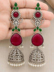 Both jhumka earrings held in an open palm showing full length filigree bell and pearl drops