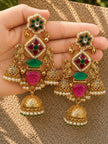 Both gold-plated chandbali jhumka earrings held in palm showing front detail with green and pink stones