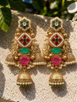 Pair of kundan jhumka earrings laid flat on stone surface in natural sunlight showing full front view