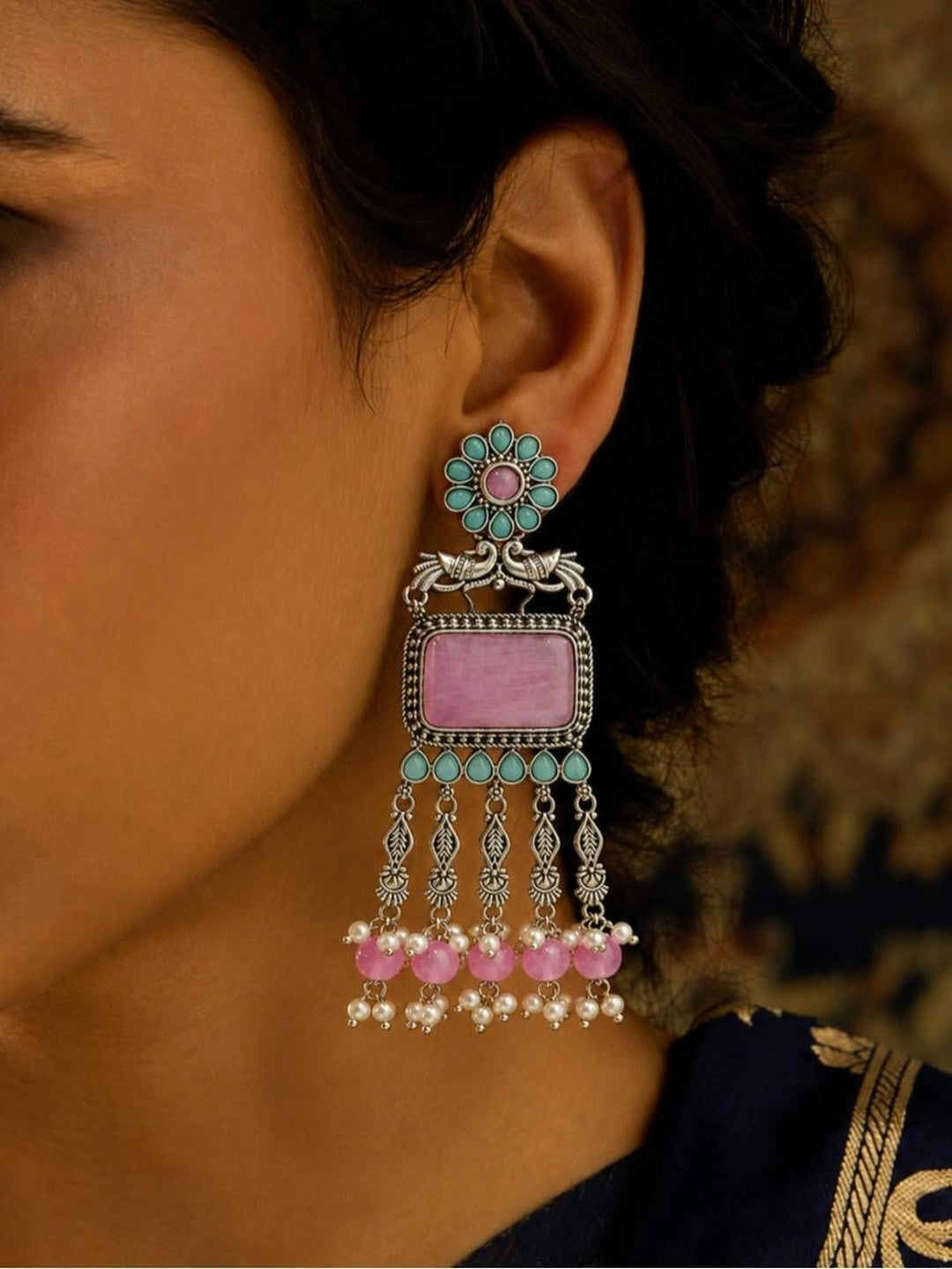 Oxidised silver chandbali earring with pink stone and turquoise accents worn on a woman's ear against a blue ethnic outfit