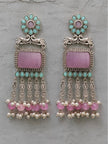 Front view of oxidised silver chandbali earrings with turquoise teardrop accents and pink bead tassels on a grey surface