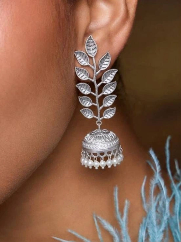 Oxidised silver leaf jhumka earring worn on ear with pearl drops and blue feathered outfit