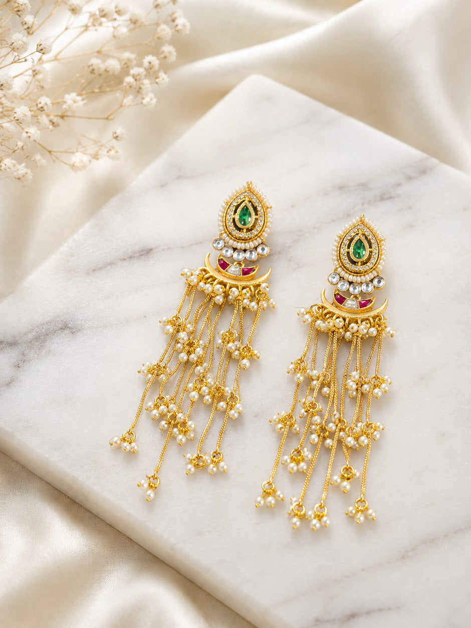 Kundan chandbali earrings with pearl chain tassels displayed flat on a white marble surface
