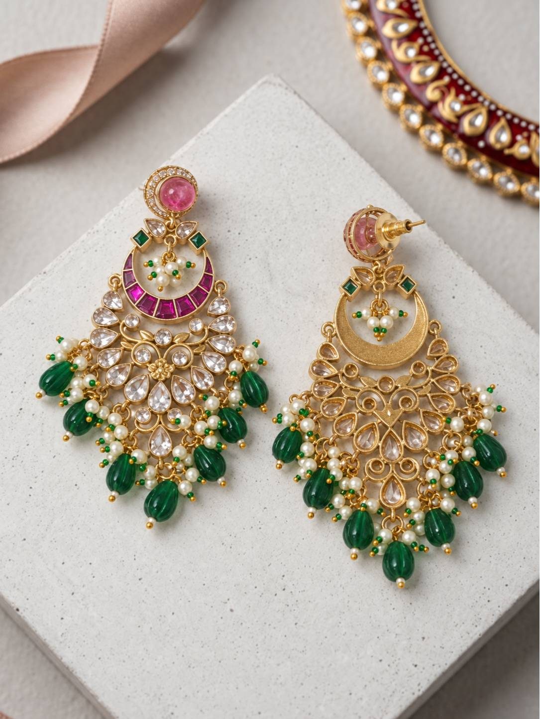 Kundan chandbali earring pair on white surface showing front and reverse sides revealing gold filigree framework and green melon-cut bead drops