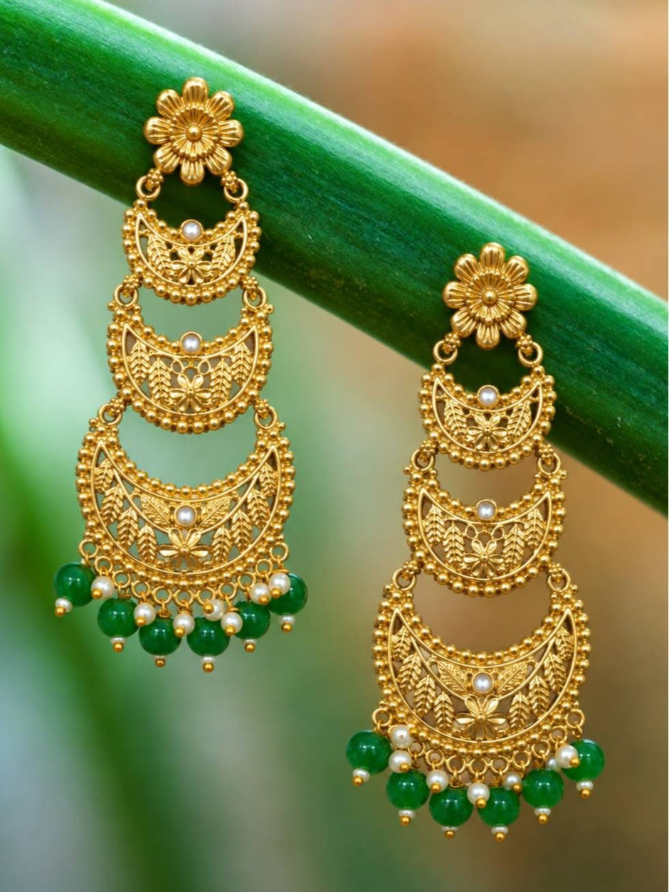 Pair of gold-plated four-tier chandbali earrings with green beads hanging on a green stem