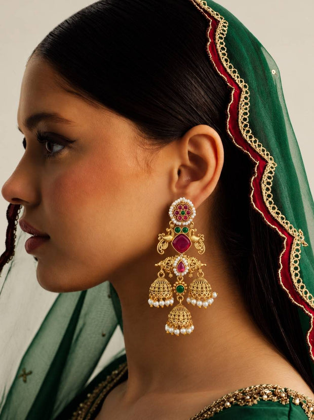 Model wearing gold-plated triple jhumka earring with pink and green stones paired with green dupatta and embroidered blouse