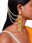 Close-up side profile of a woman wearing gold-plated multi-disc jhumka with three-strand pearl chain in her dark hair
