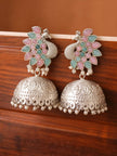 Pair of oxidised silver peacock jhumka earrings with pink and mint green stones on a wooden surface