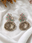 Two oxidised silver peacock jhumka earrings laid flat on white fabric showing engraved dome and pearl fringe