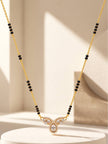 Full-length view of gold-plated black bead mangalsutra hanging against a minimal beige backdrop
